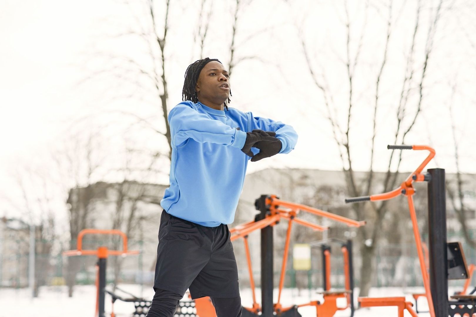 Person värmer upp i ett snötäckt utegym med orange redskap